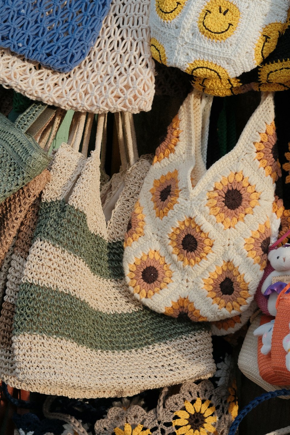 Handmade crocheted bags with floral and smiley face patterns.