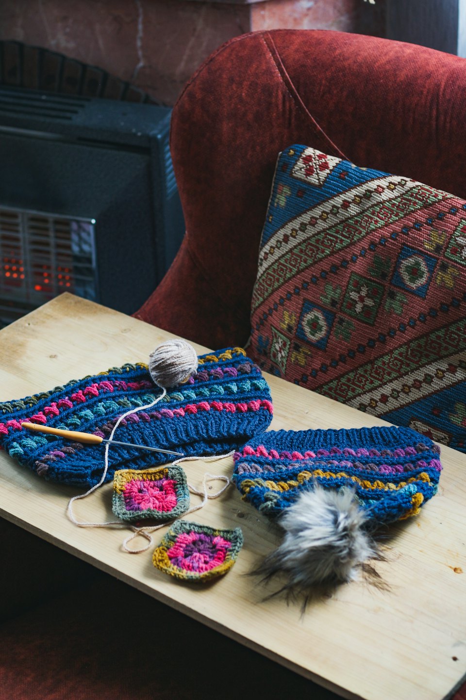 Crocheted accessories and yarn arranged on a wooden table.